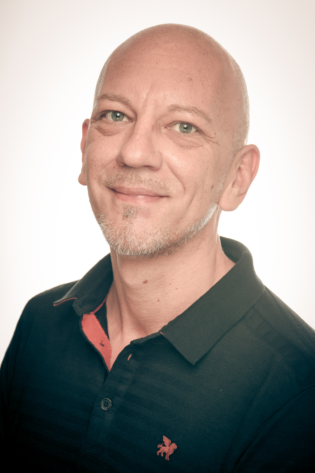 "Porträtfoto einer lächelnden Person vor hellem Hintergrund."